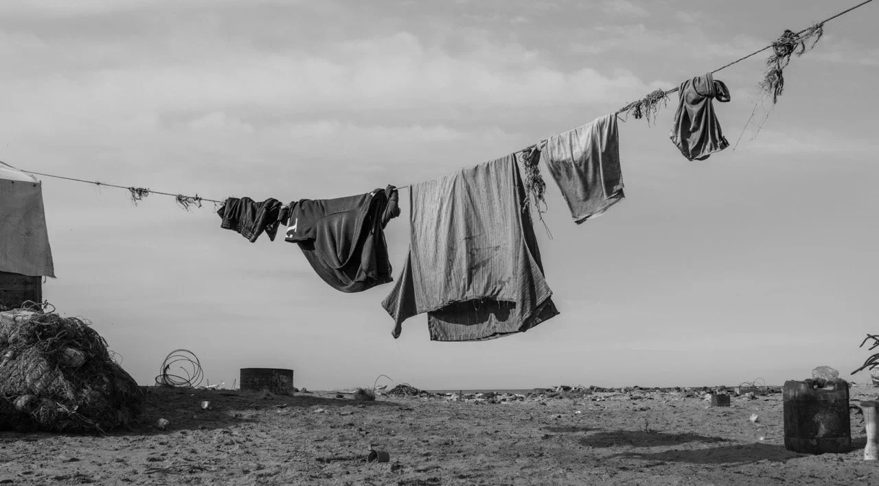 Clothes hanging on a line on a beach, in black and white.