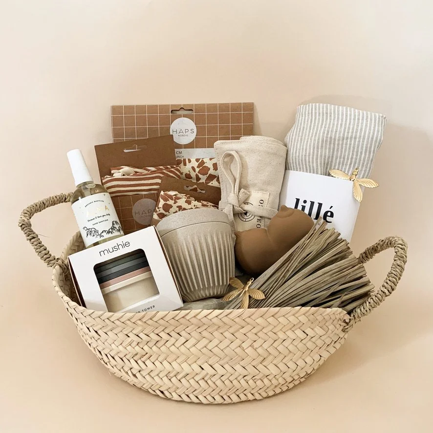 Decorative gift basket containing home decor items, toiletries, and accessories in neutral tones.