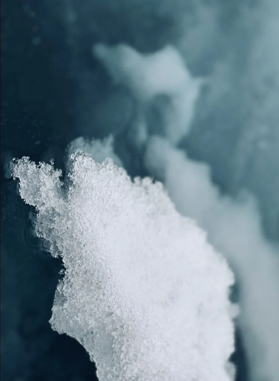 Close-up of salt or snow on a blue surface with steam rising behind it.