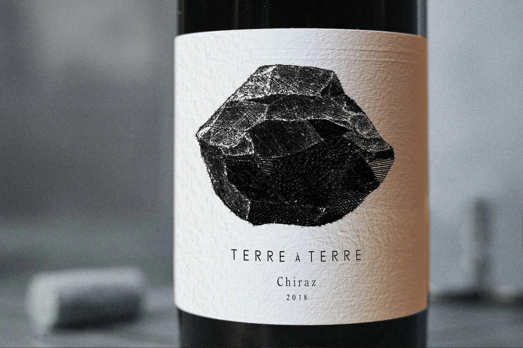 Wine bottle label with a black geometric stone illustration, text 'TERRE À TERRE', 'Chiraz', and '2018'.