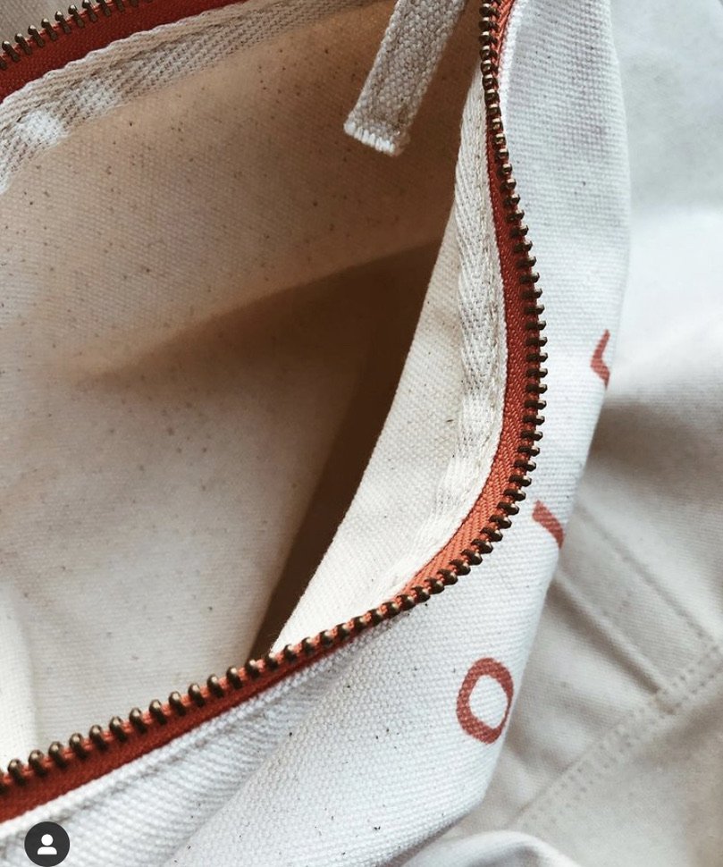 Close-up of an open canvas bag with a zipper, showing the inside which appears to have small specks and a fabric lining.