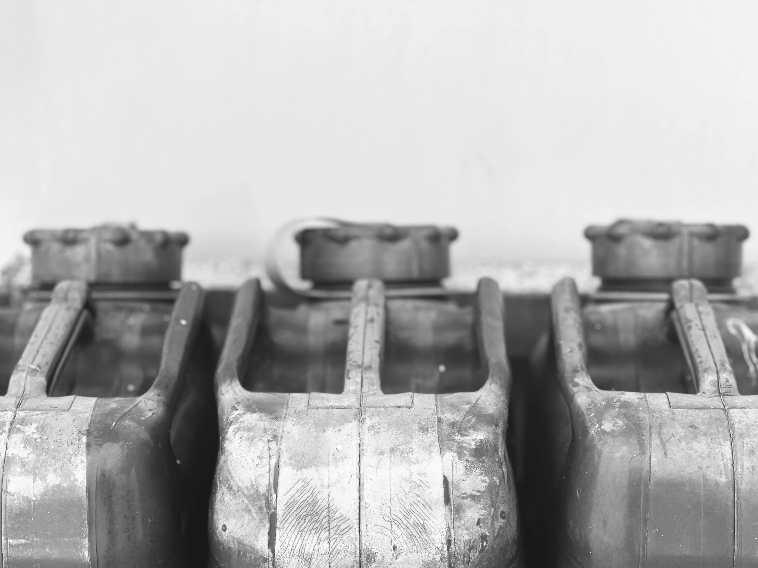 Close-up of three old, damaged cans placed side by side against a plain background.
