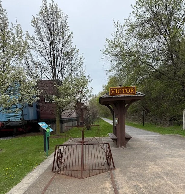 A train sculpture, kiosk, and seating can be found at the Maple Ave trail crossing.