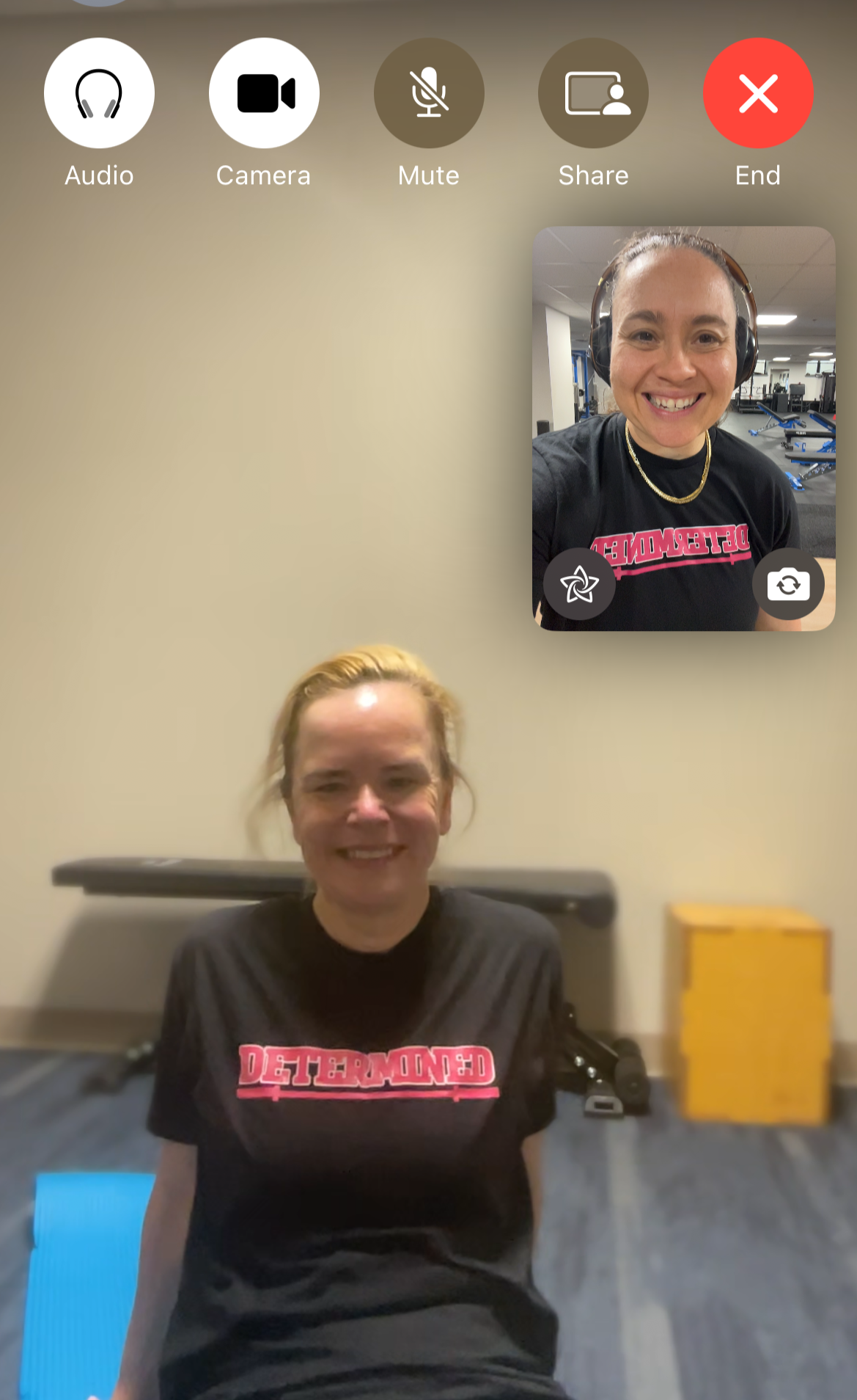 Two women on a video call, one sitting at a piano in a room with a yellow cabinet, the other wearing headphones and smiling in a gym with exercise equipment.