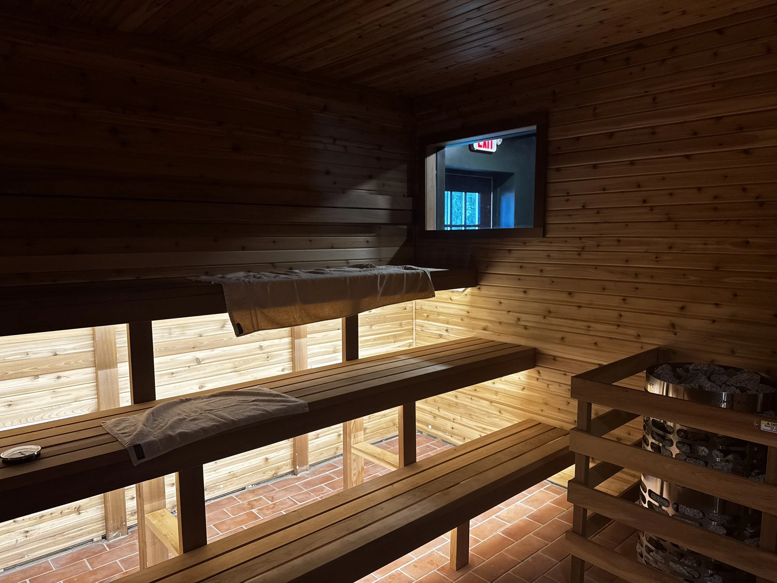 Cedar benches and the stone heater inside the Finnish sauna at Gainesville Sauna House