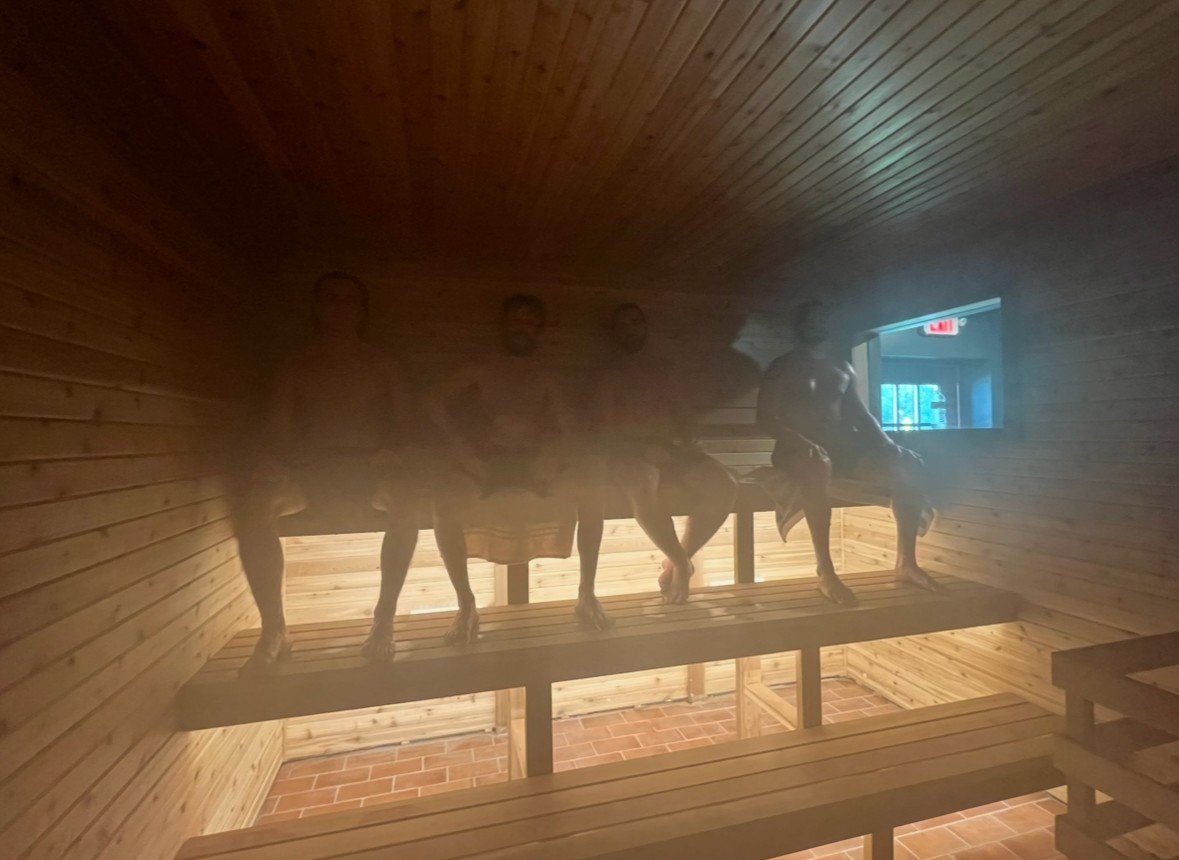 Steam rising in the Finnish sauna, with bathers resting on the cedar benches
