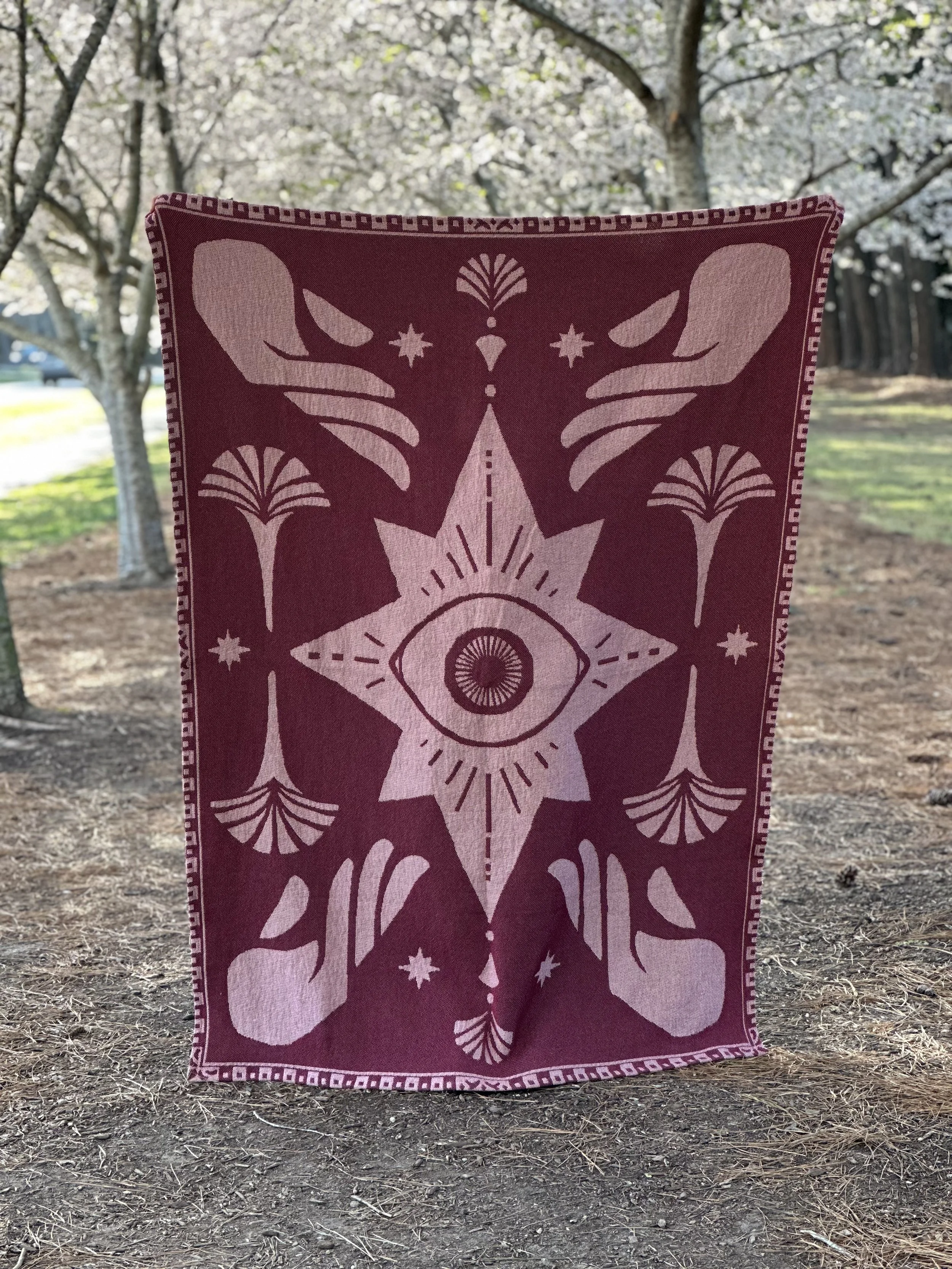 This image shows the blanket upside down. Nothing is changed except for the four hands on each corner of the blanket are now palm up. Perhaps beckoning instead of reaching, or exhalting