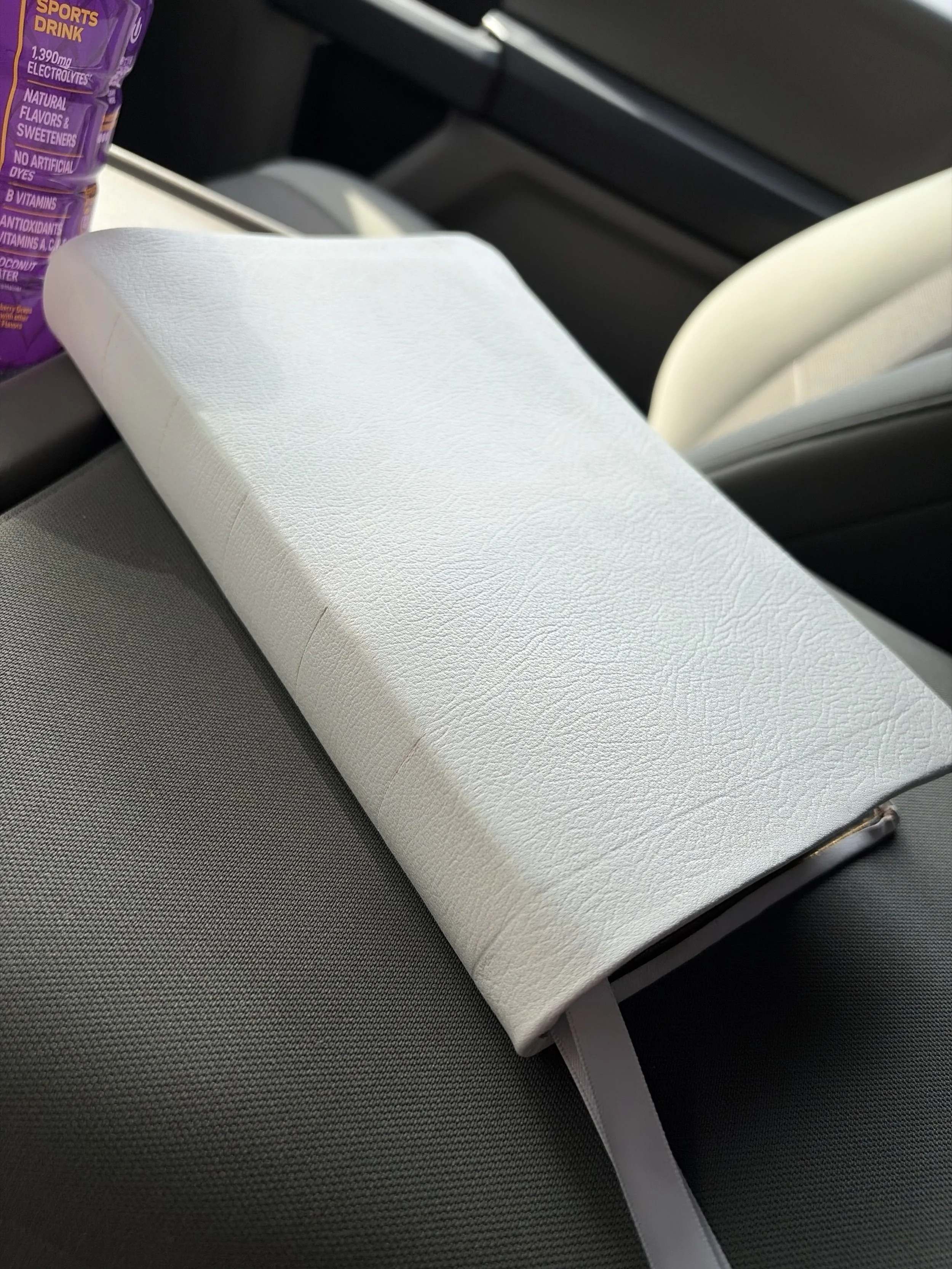 A white rectangular box with a textured surface resting on a car seat.