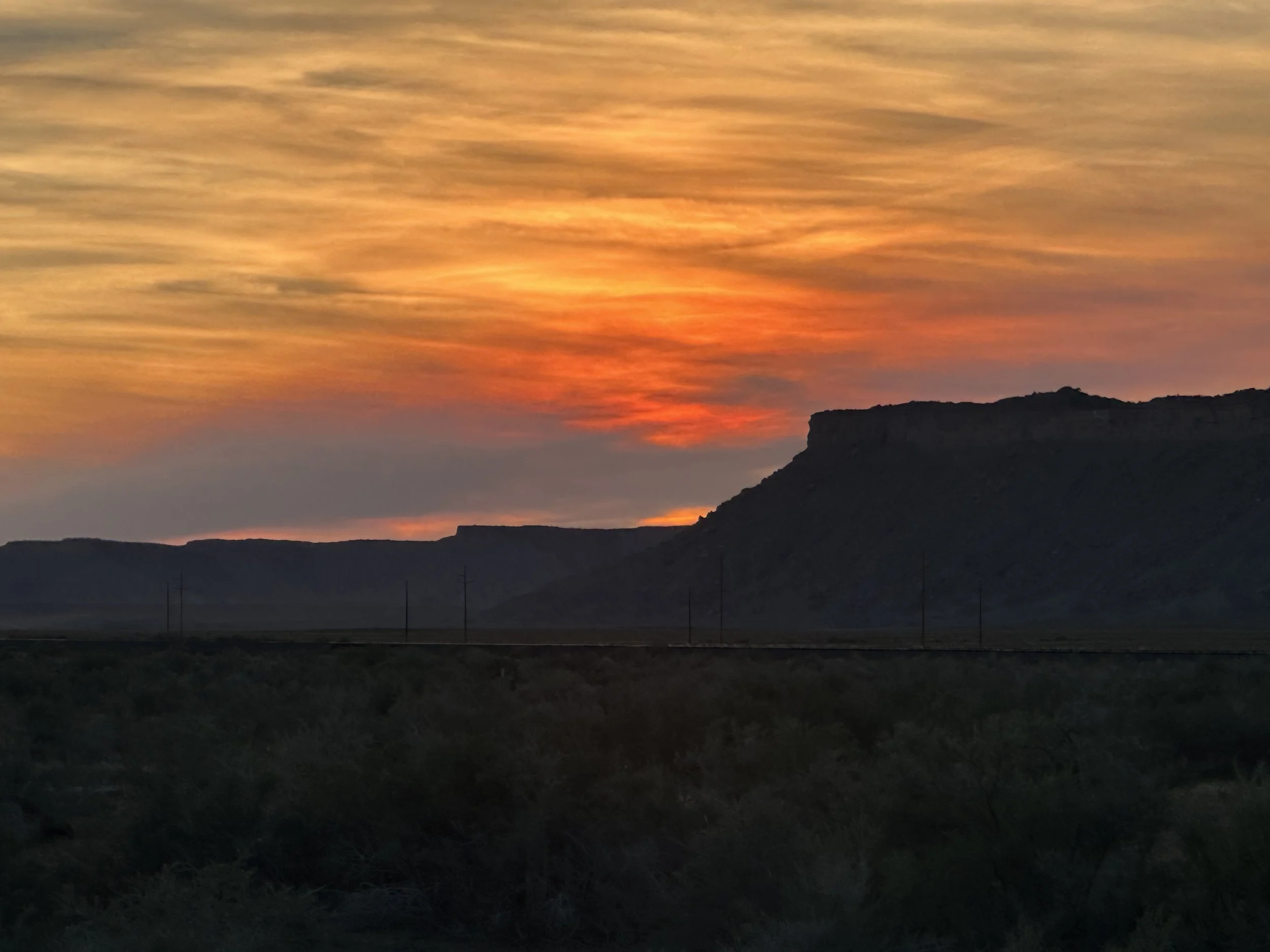 A sunset or sunrise over a mountainous landscape with colorful clouds in the sky.