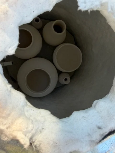 Several raku pottery vessels in a homemade garbage can raku kiln.
