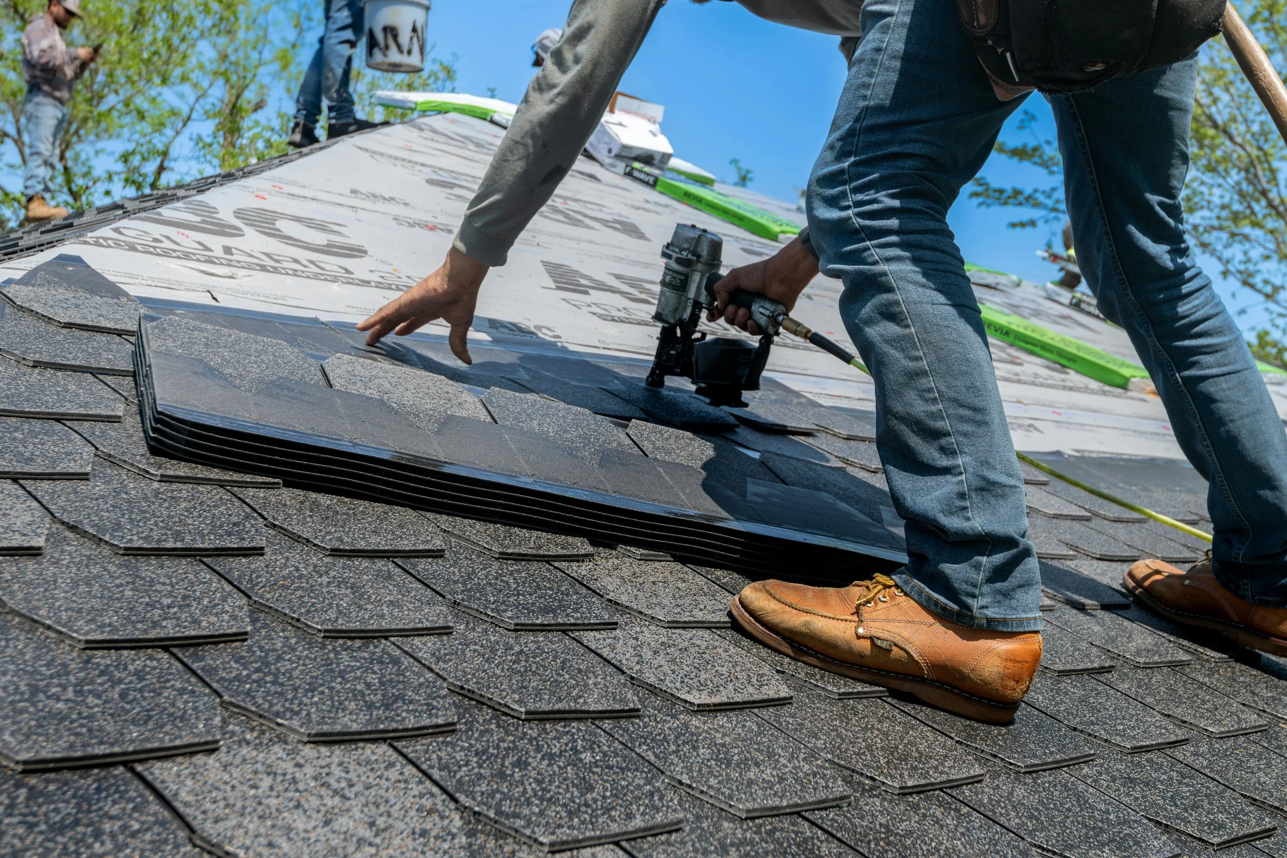 Roofing crew installing asphalt shingles on a residential roof.