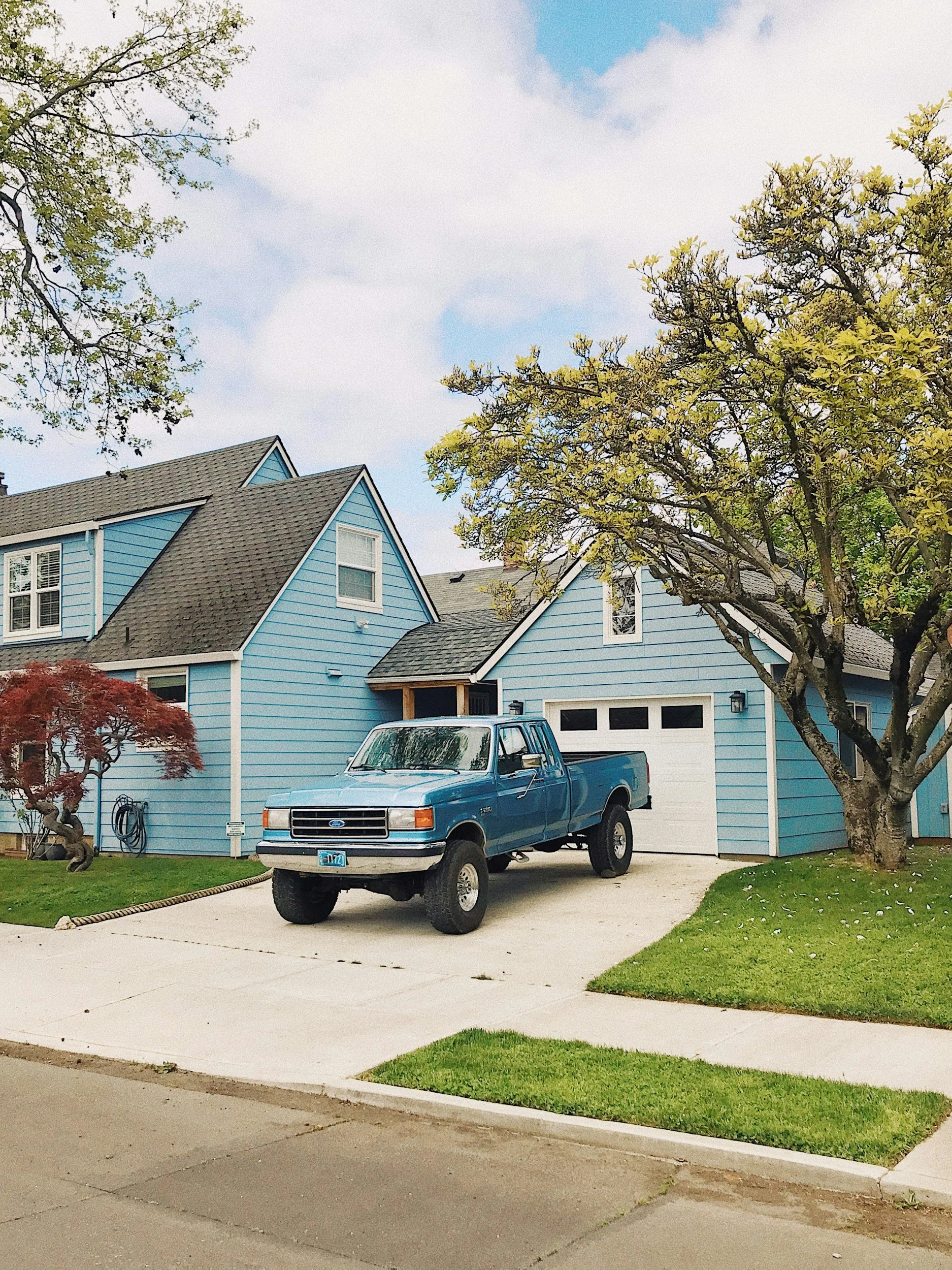 Blue home with grey asphalt shingles and blue truck