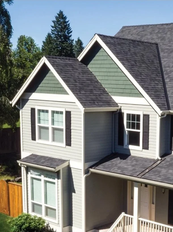 Residential home with gray siding, white trim, and dark asphalt shingle roof.