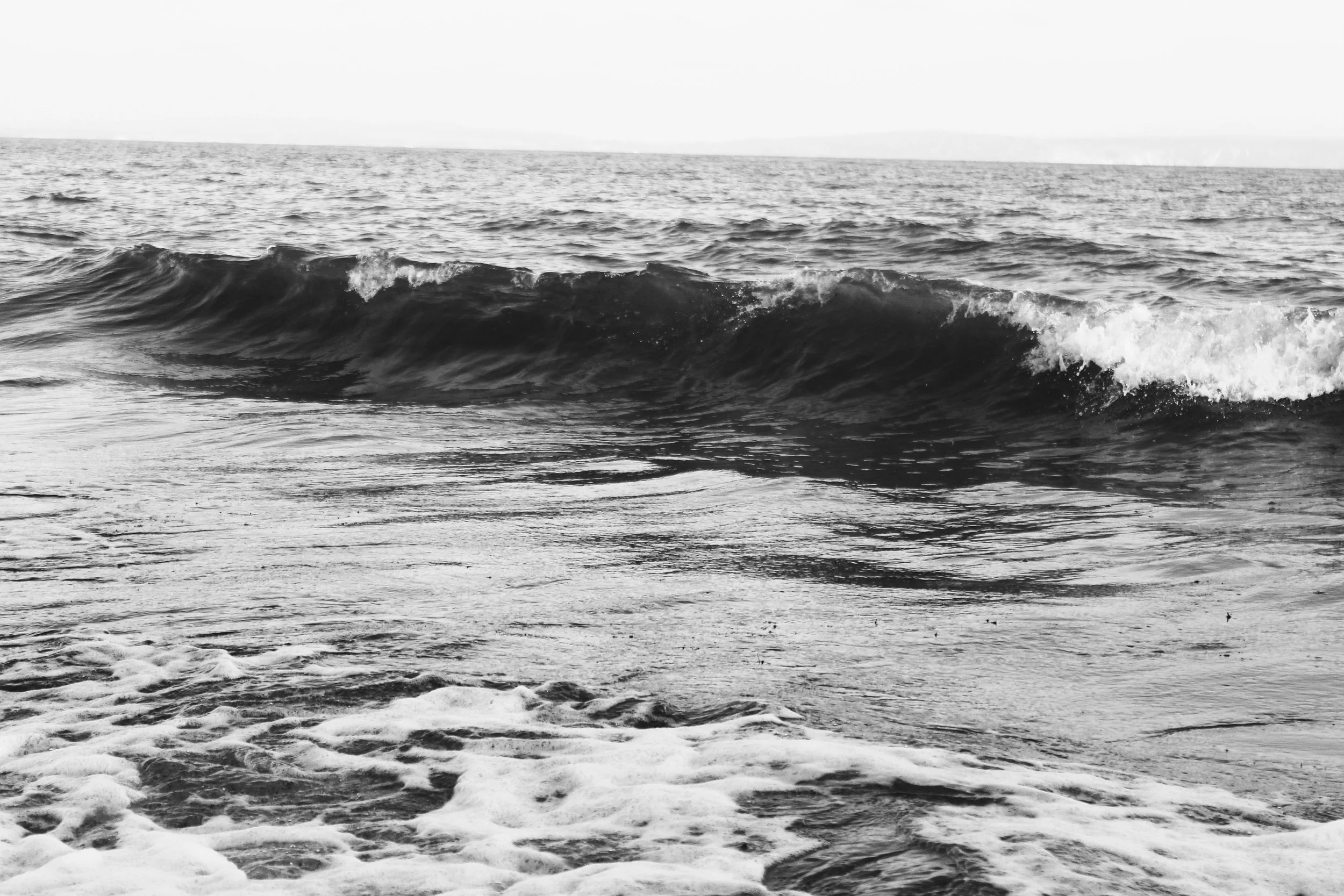 Black and white photograph of ocean waves crashing onto the shore.