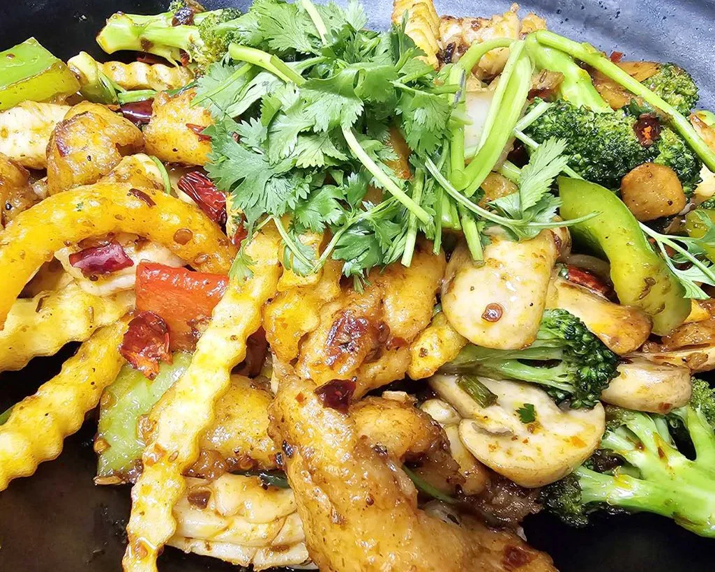 Close-up of a colorful stir-fried vegetable dish with broccoli, baby corn, bell peppers, and fresh cilantro garnish.