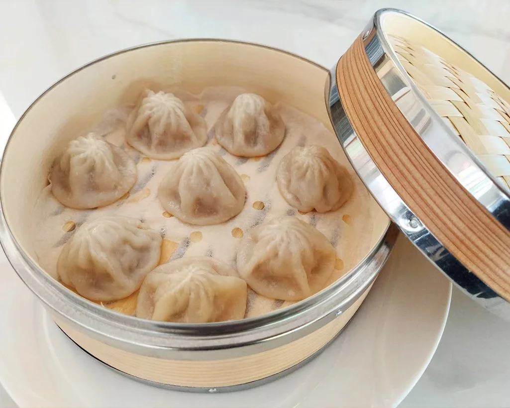 Steamed dumplings inside a traditional bamboo steamer basket.