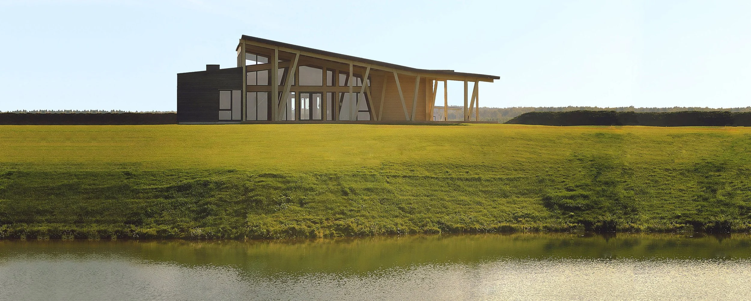 Modern golf clubhouse with large glass windows and wooden beams near a body of water, surrounded by green grass and landscape.