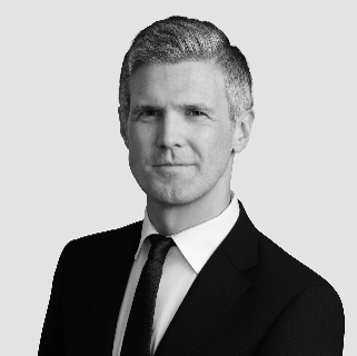 Black and white portrait of a man in a suit and tie, looking confidently at the camera.