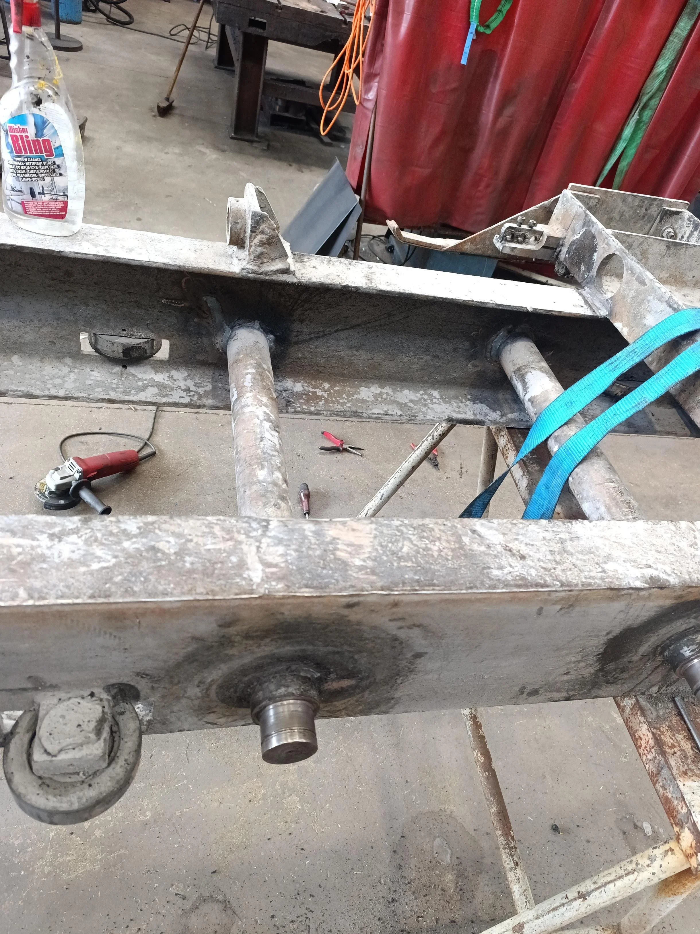Une machine de travail métallique en cours de restauration avec outils et pièces autour dans un atelier.