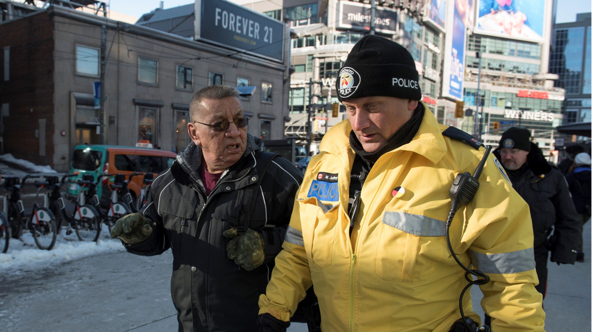 Toronto police officer speaking with a community member in a downtown public space as part of neighbourhood community policing.