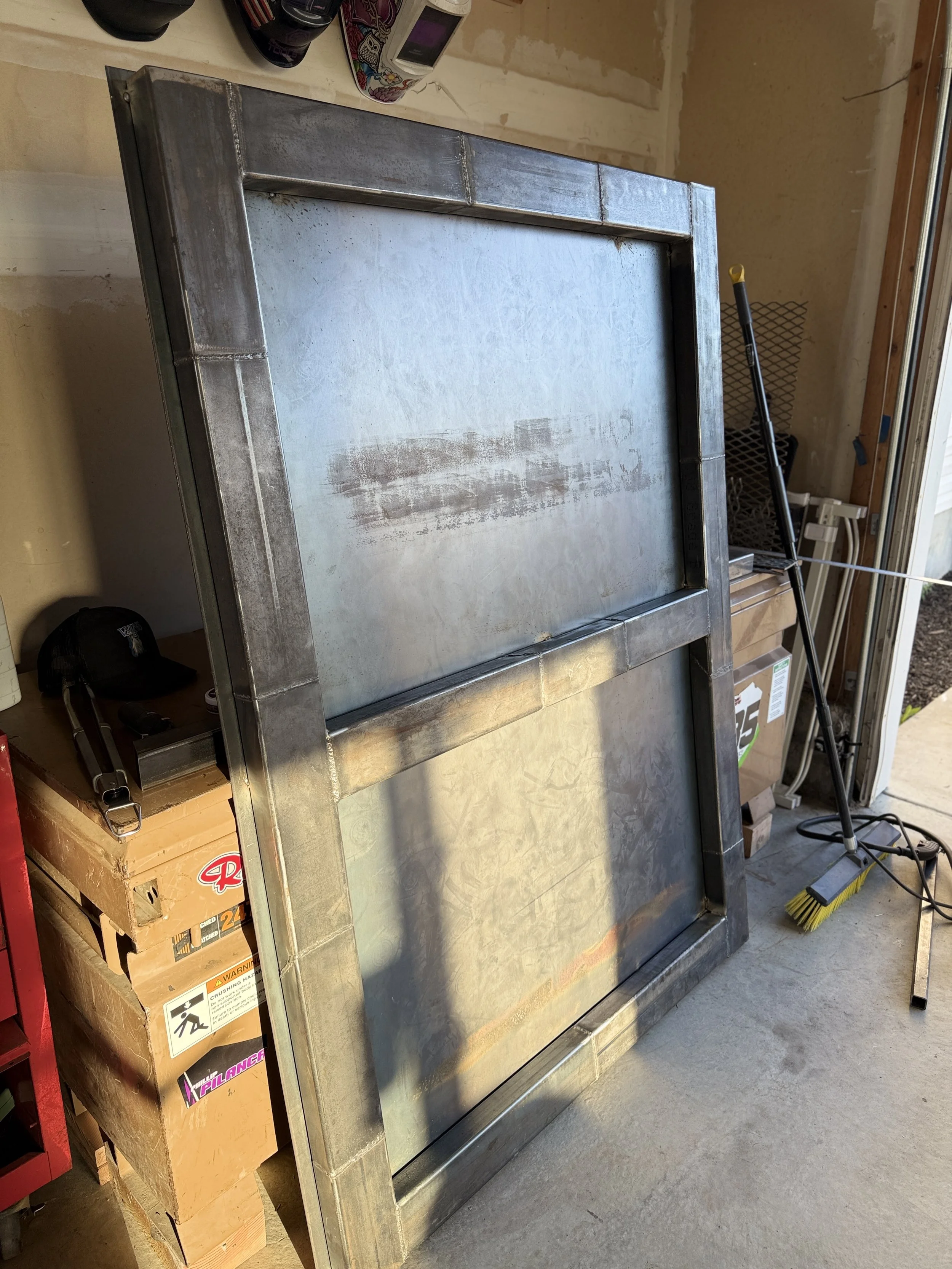 A metal smoker or oven with a door in a garage or workshop, with various tools and boxes nearby.