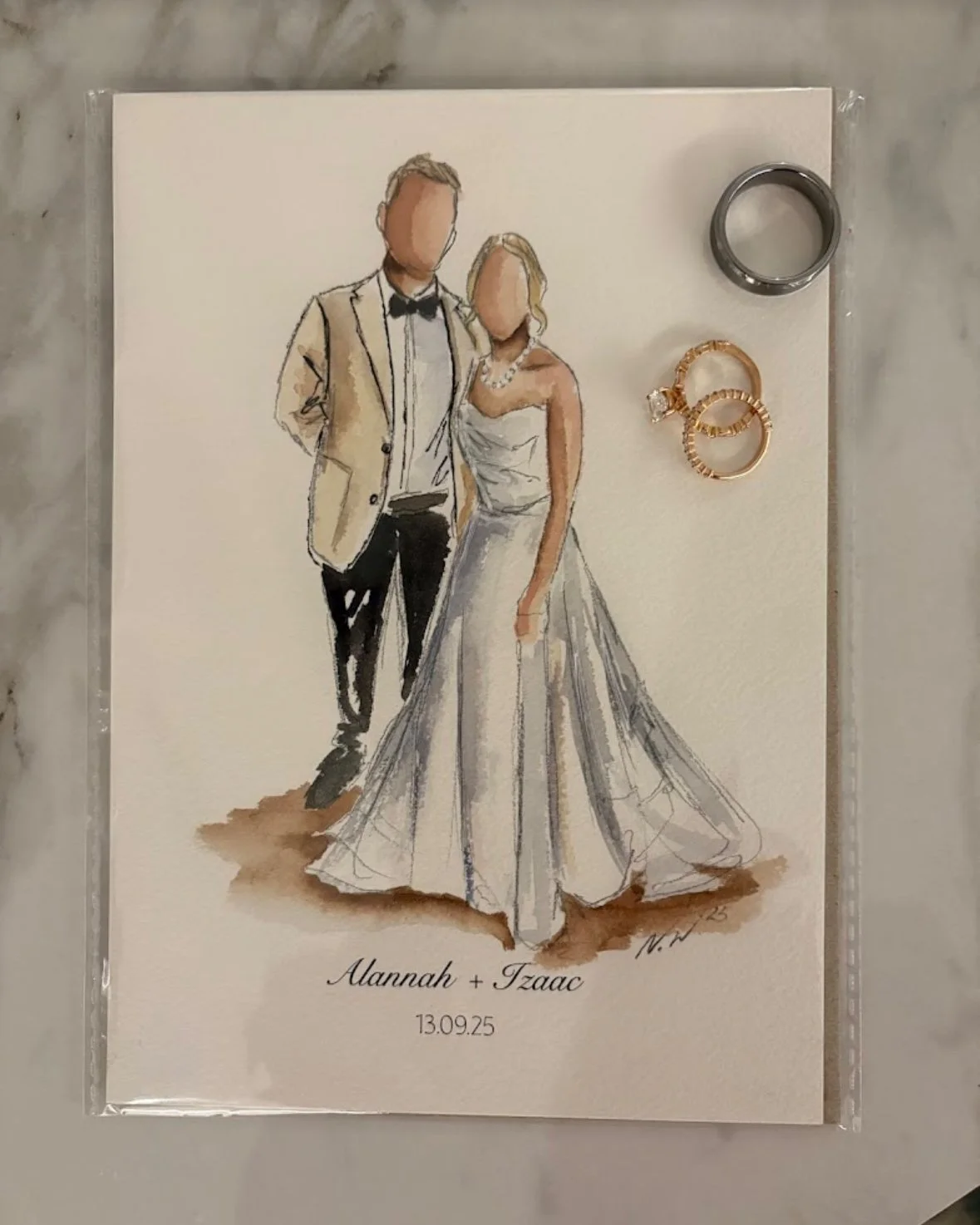 Watercolor illustration of a bride and groom at their wedding, with the date 13.09.25 and names Alannah and Tzaac written below, along with wedding rings placed on the right side.