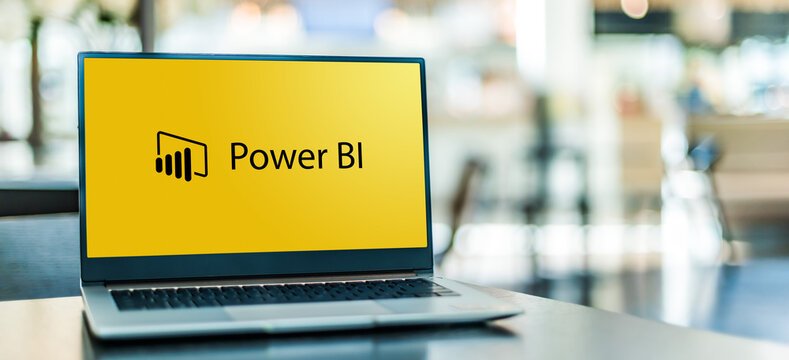 Open laptop displaying the Power BI logo and text on a desk in a modern office setting.