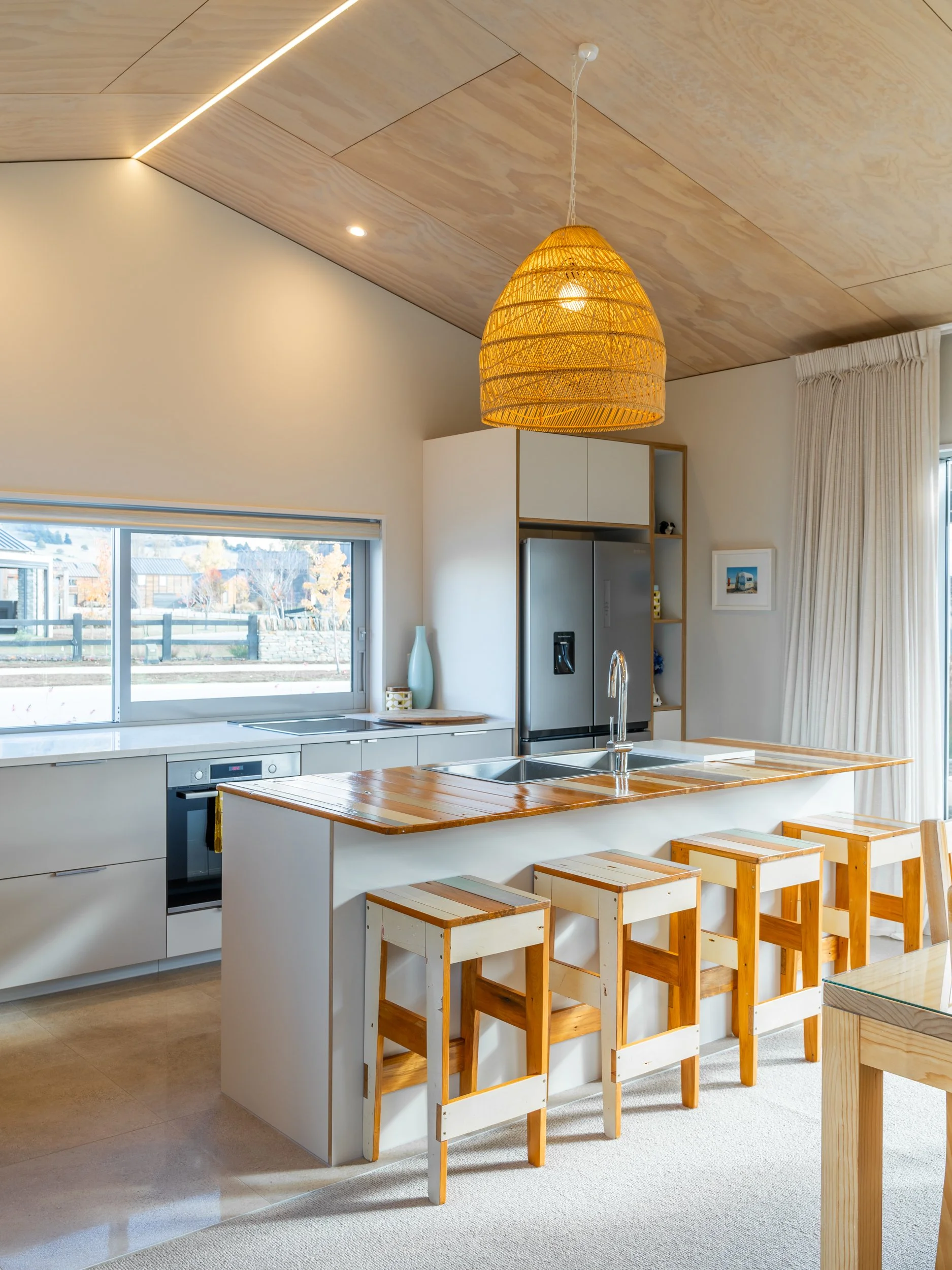 Light-filled kitchen with timber-lined ceiling, reclaimed timber bench and warm natural finishes.