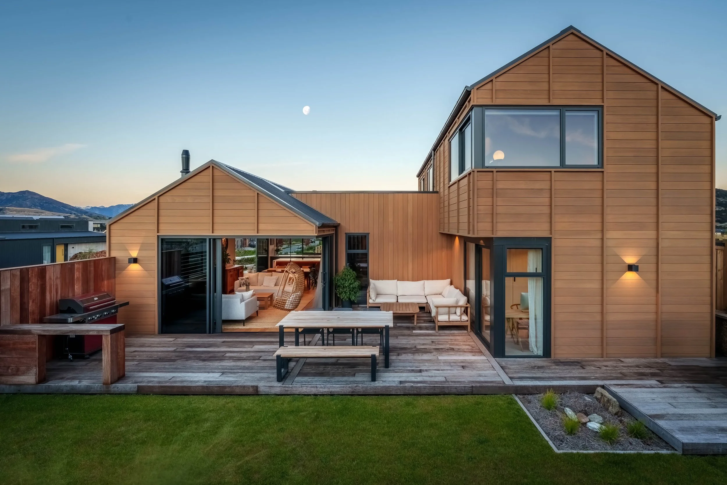 Outdoor living area of modern home in Wānaka at dusk with mountain backdrop.