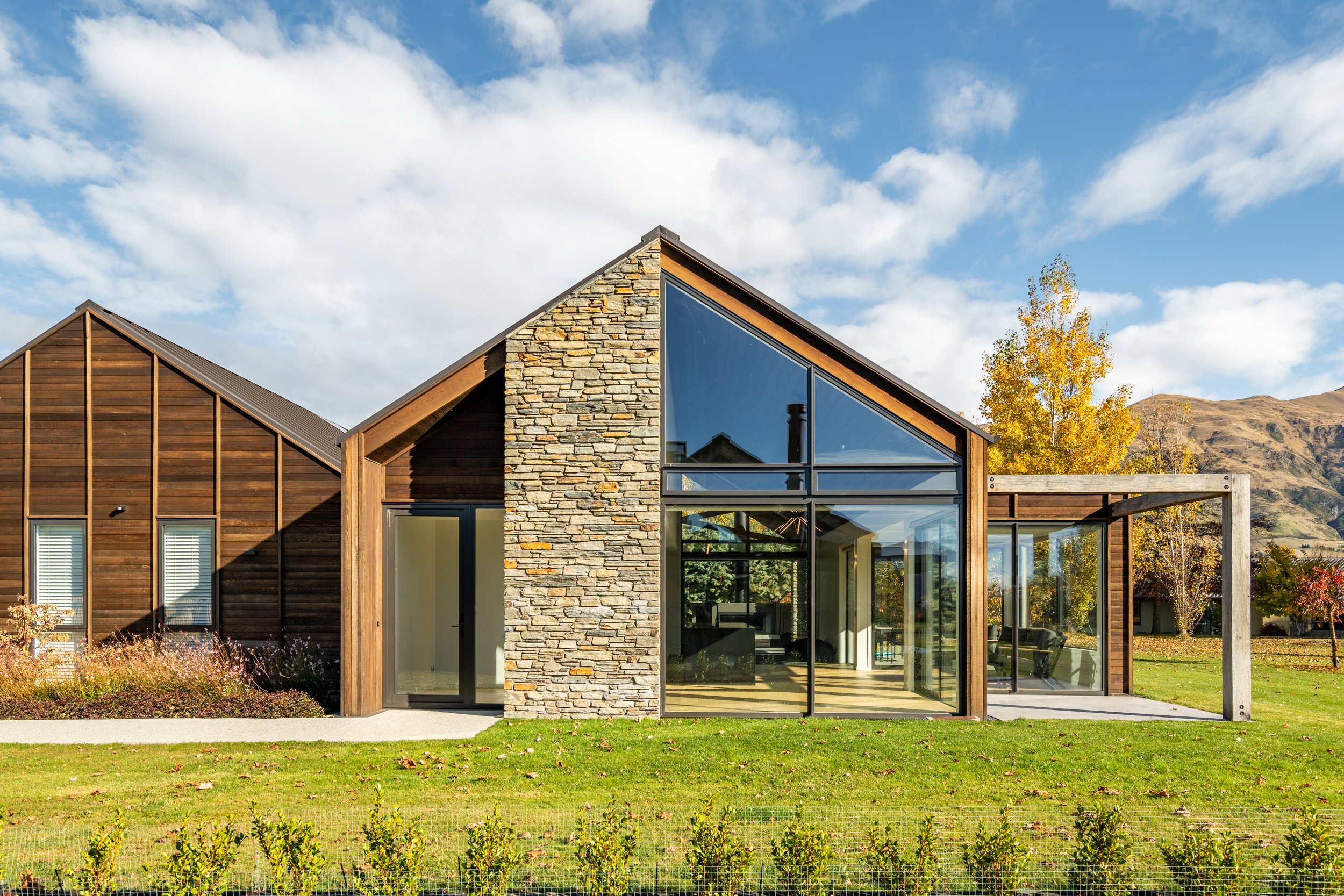 Architectural alpine-inspired home with floor-to-ceiling glazing, schist detailing and warm timber cladding.