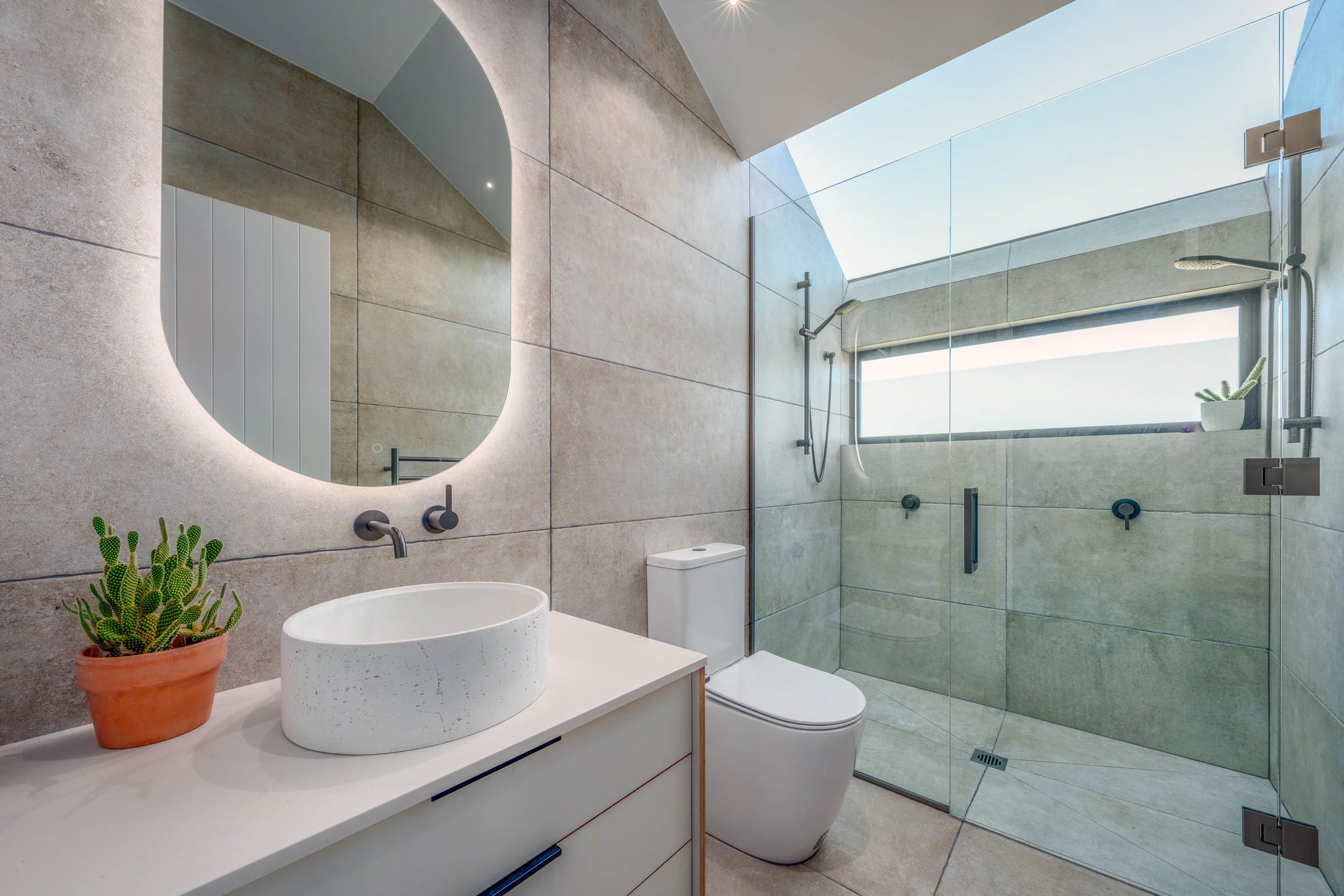 Neutrally-toned, fully tiled ensuite bathroom featuring a skylight in the double shower.  