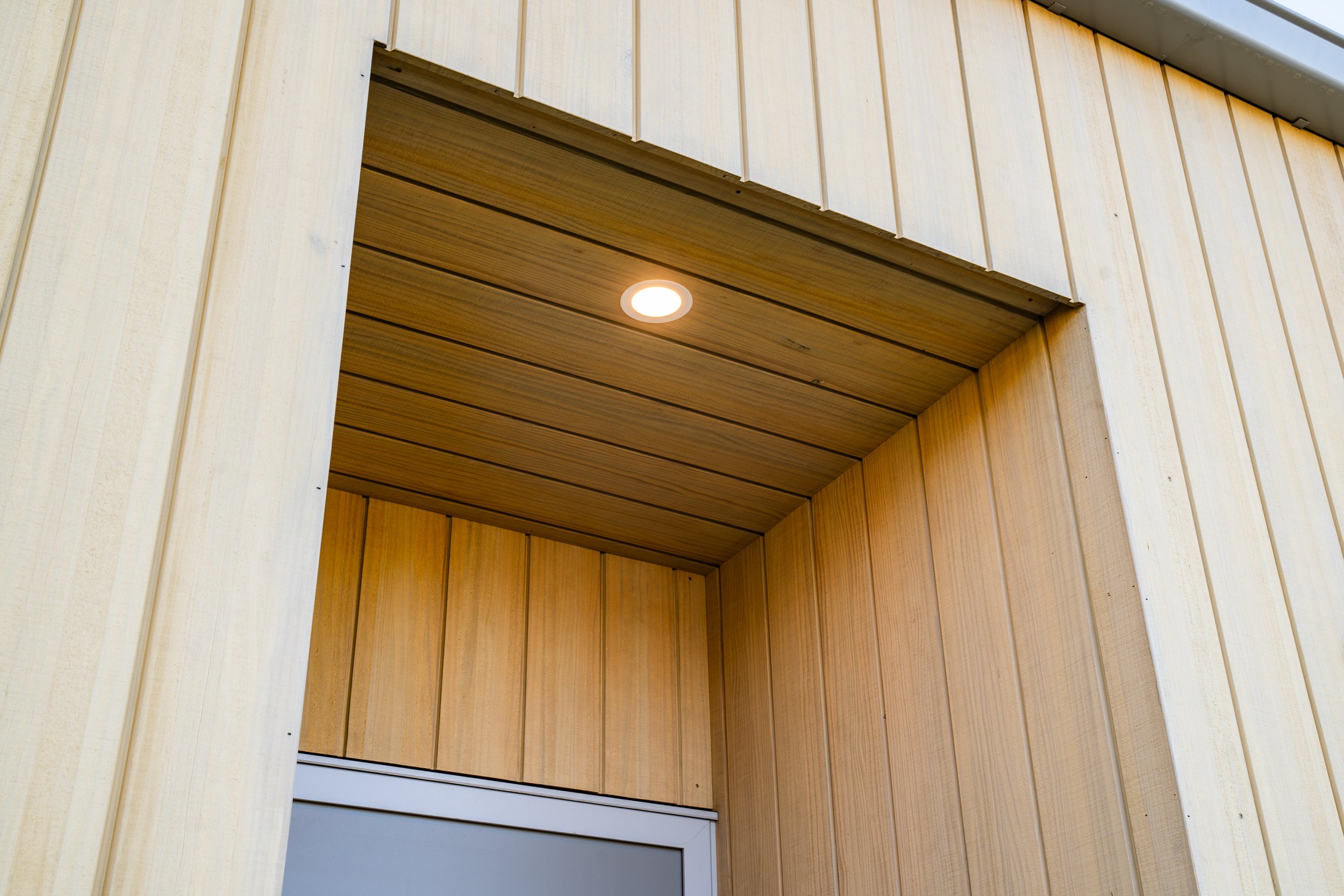 Detailed cedar cladding and recessed entry feature with integrated exterior lighting.