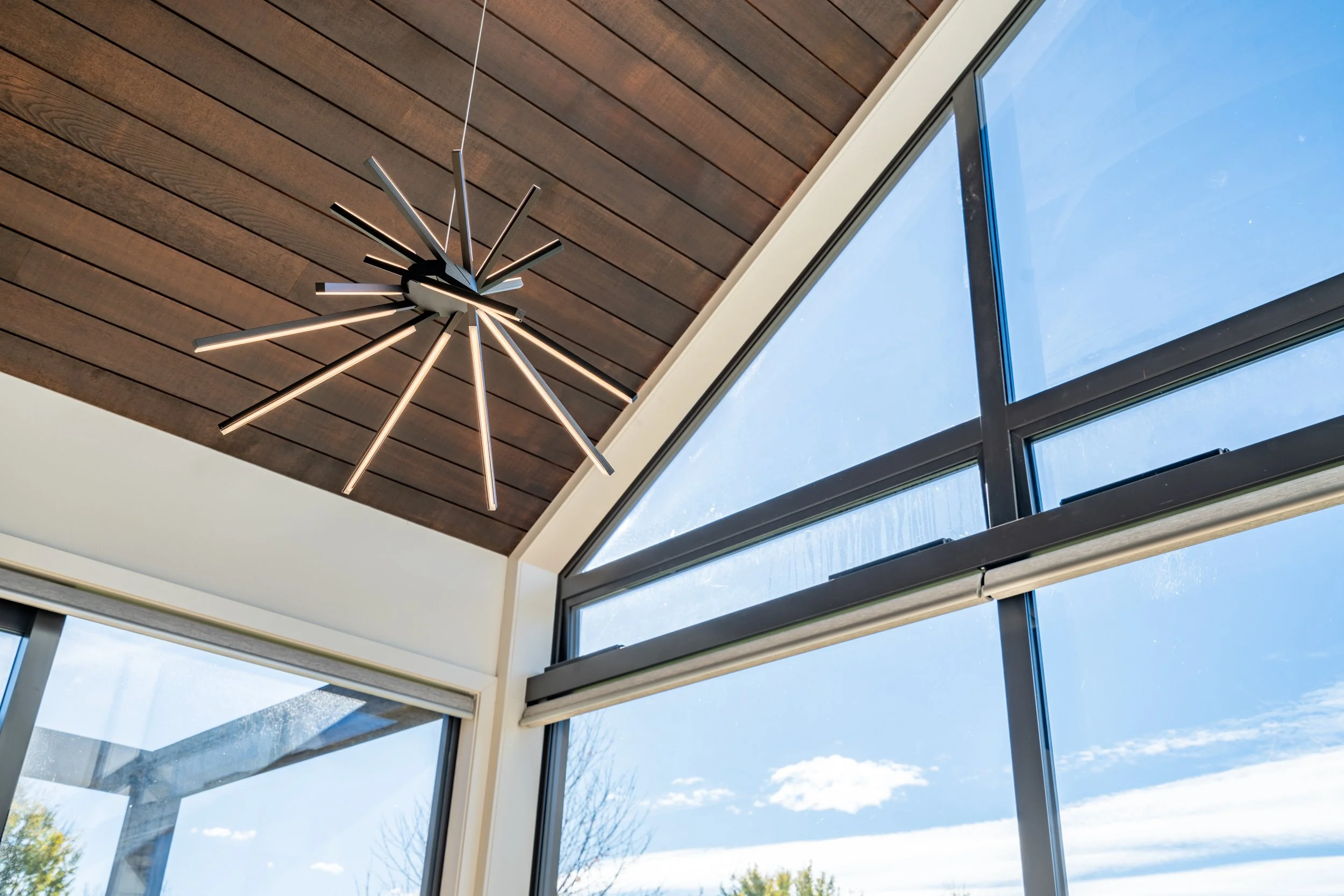 Feature timber-lined ceiling and statement lighting within the vaulted living area of Alpine Residence.
