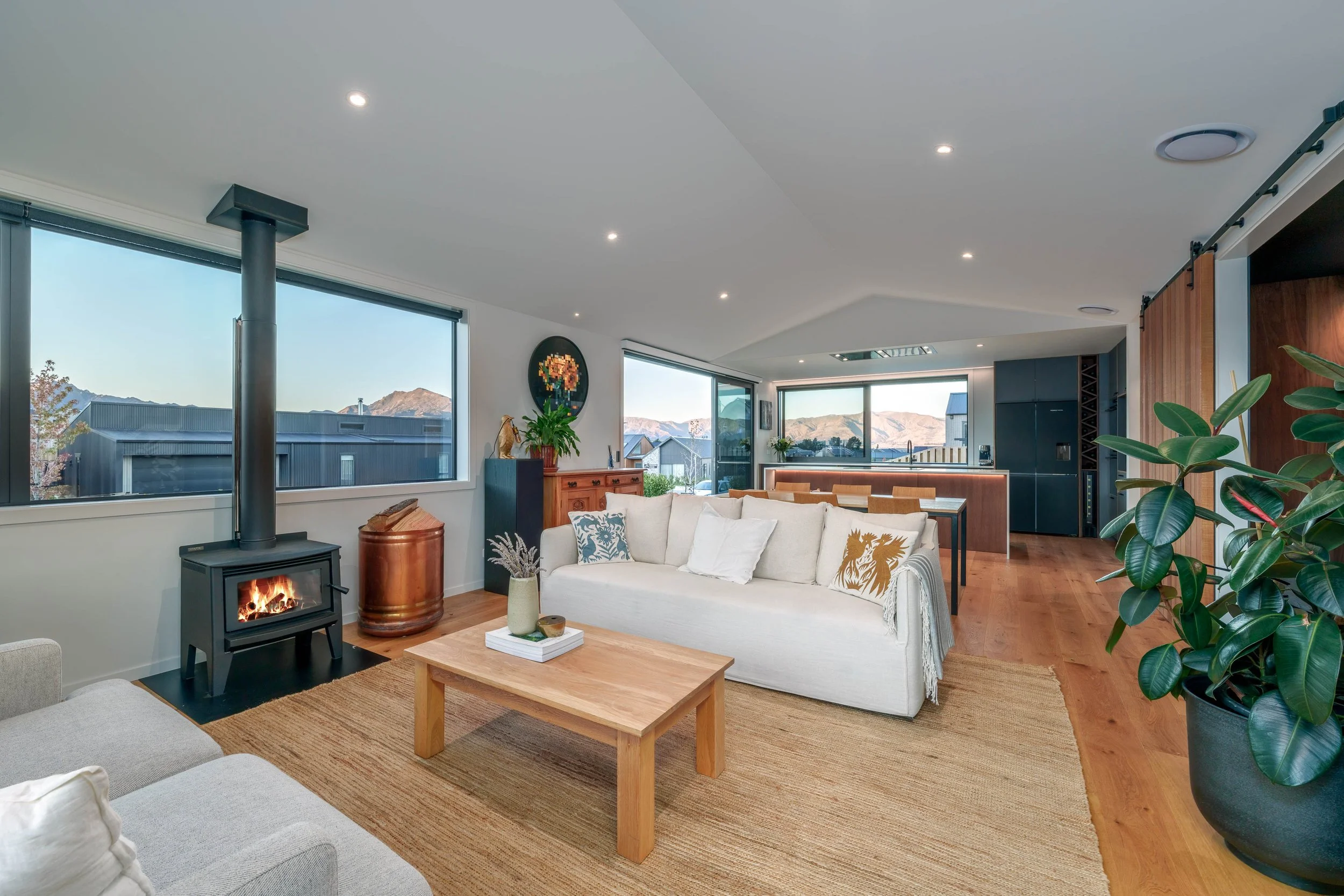 Open flow kitchen and lounge space featuring high ceilings and warm timber flooring. 