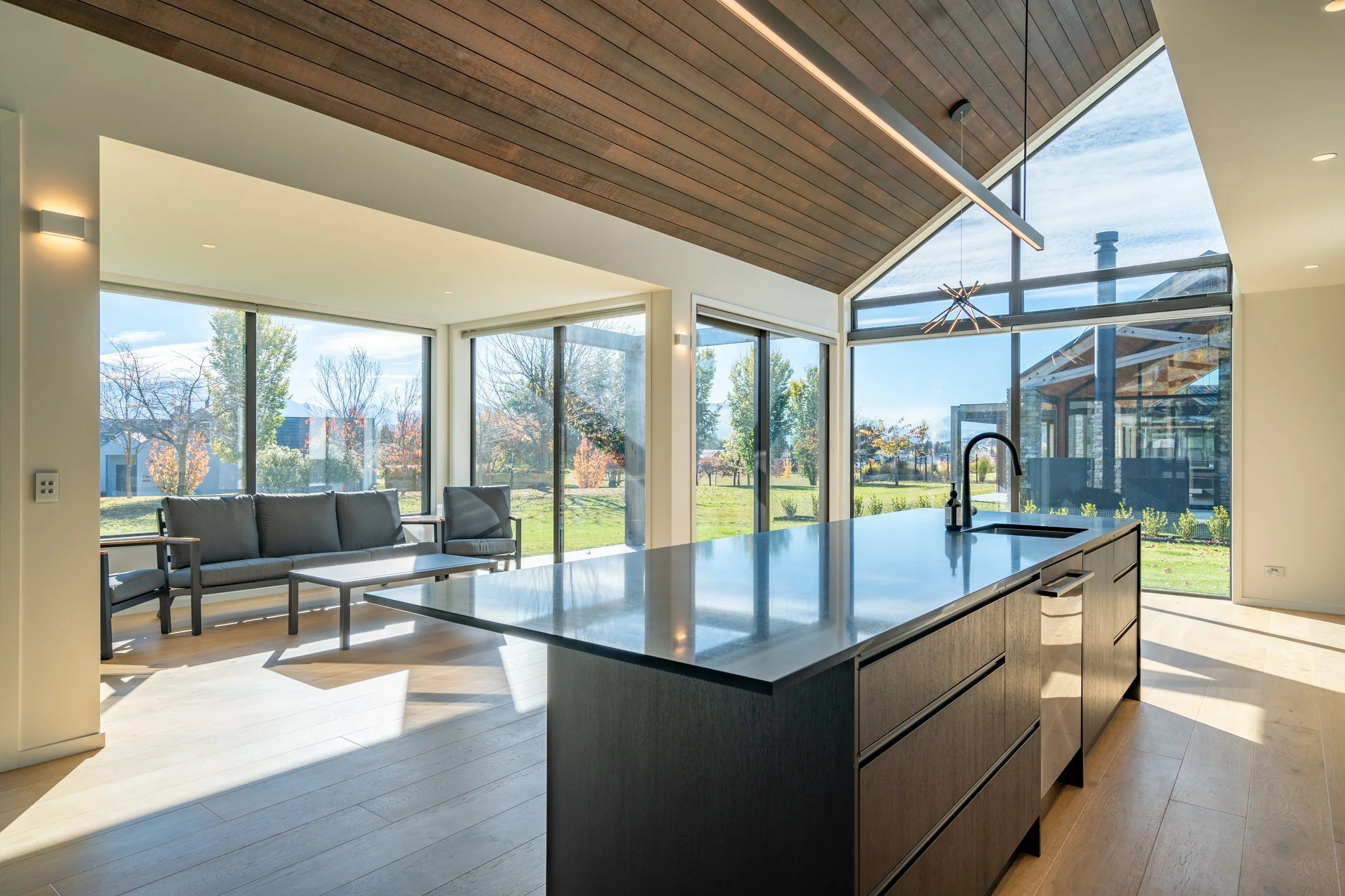 Light-filled open-plan living space with vaulted ceiling, oversized glazing and expansive alpine outlooks.