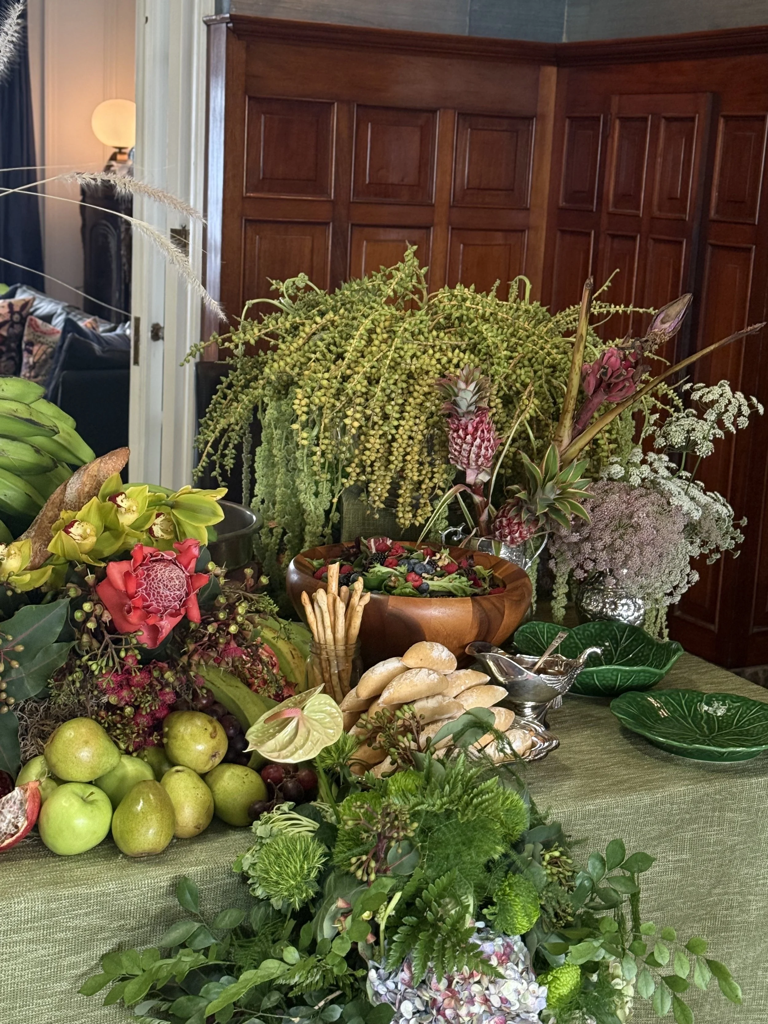 Mesa decorada con flores, frutas y platos en un ambiente interior.