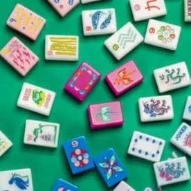 Colorful dominoes with various designs and numbers scattered on a green surface.