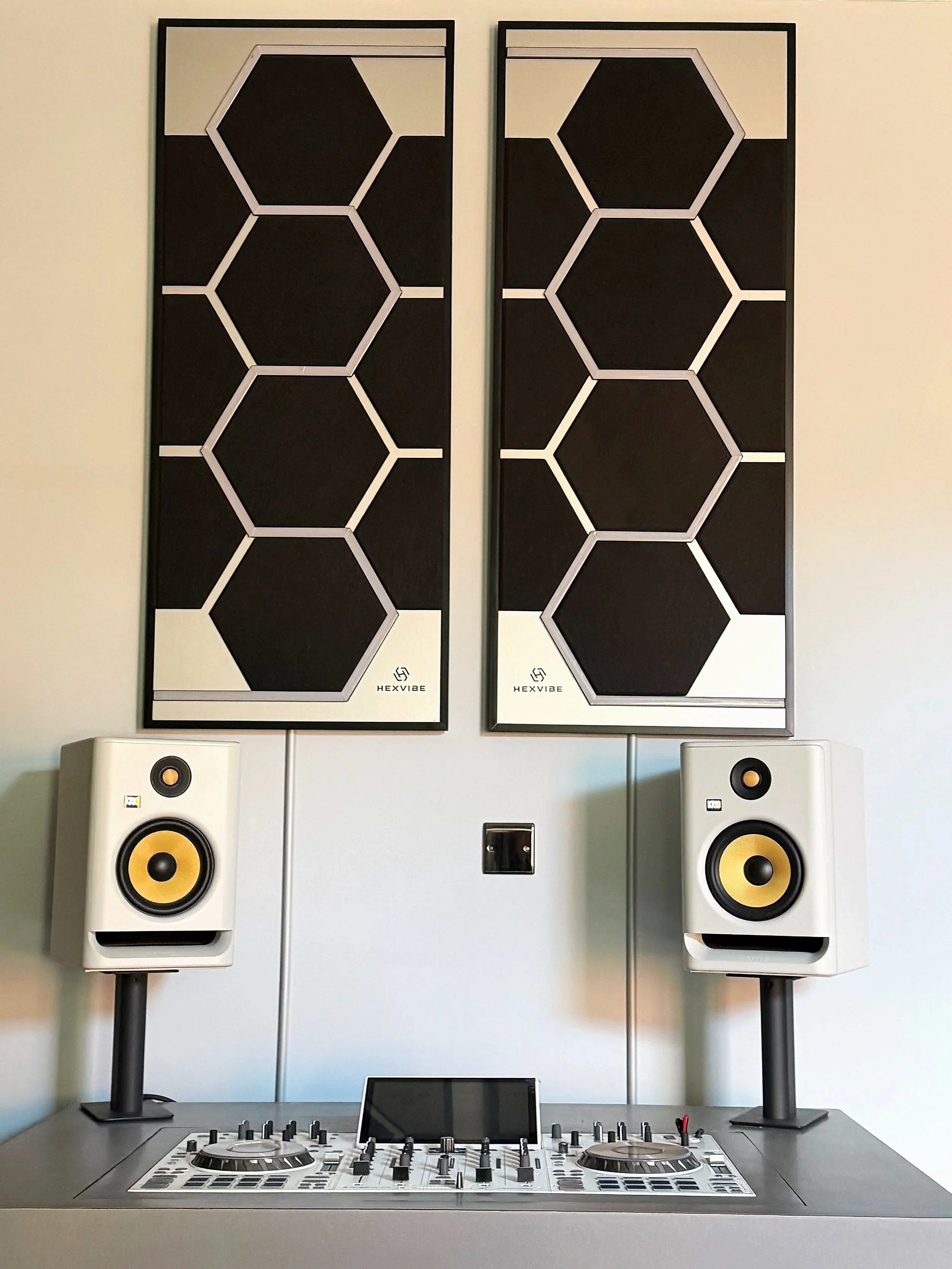 HexVIBE Flash sound-reactive LED acoustic panels installed above a professional DJ booth with studio monitor speakers, combining immersive lighting with acoustic treatment.