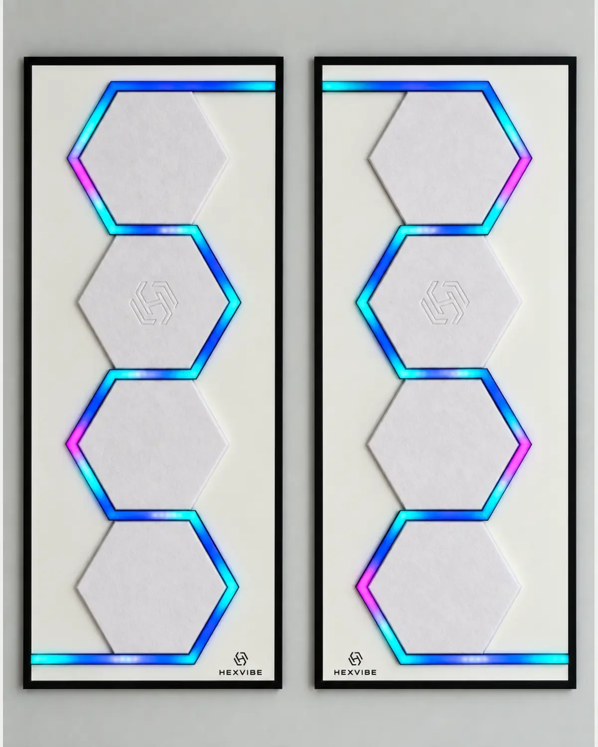 Two illuminated HexVIBE FLOW Arctic sound-reactive LED acoustic wall panels arranged as a mirrored pair with white hexagons and blue, cyan and magenta lighting
