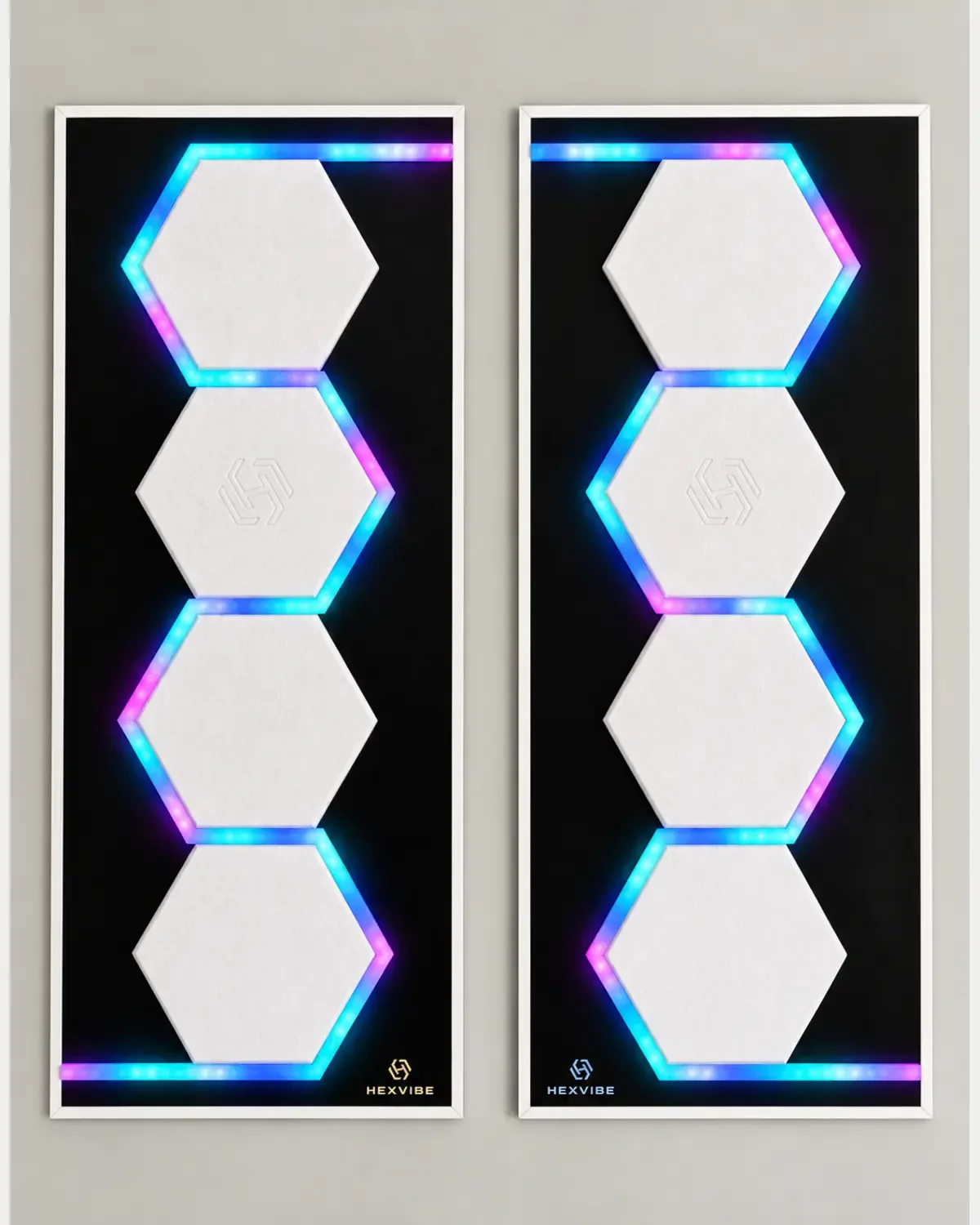 Two illuminated HexVIBE FLOW Polar sound-reactive LED acoustic wall panels arranged as a mirrored pair with white hexagons and blue, cyan and magenta lighting
