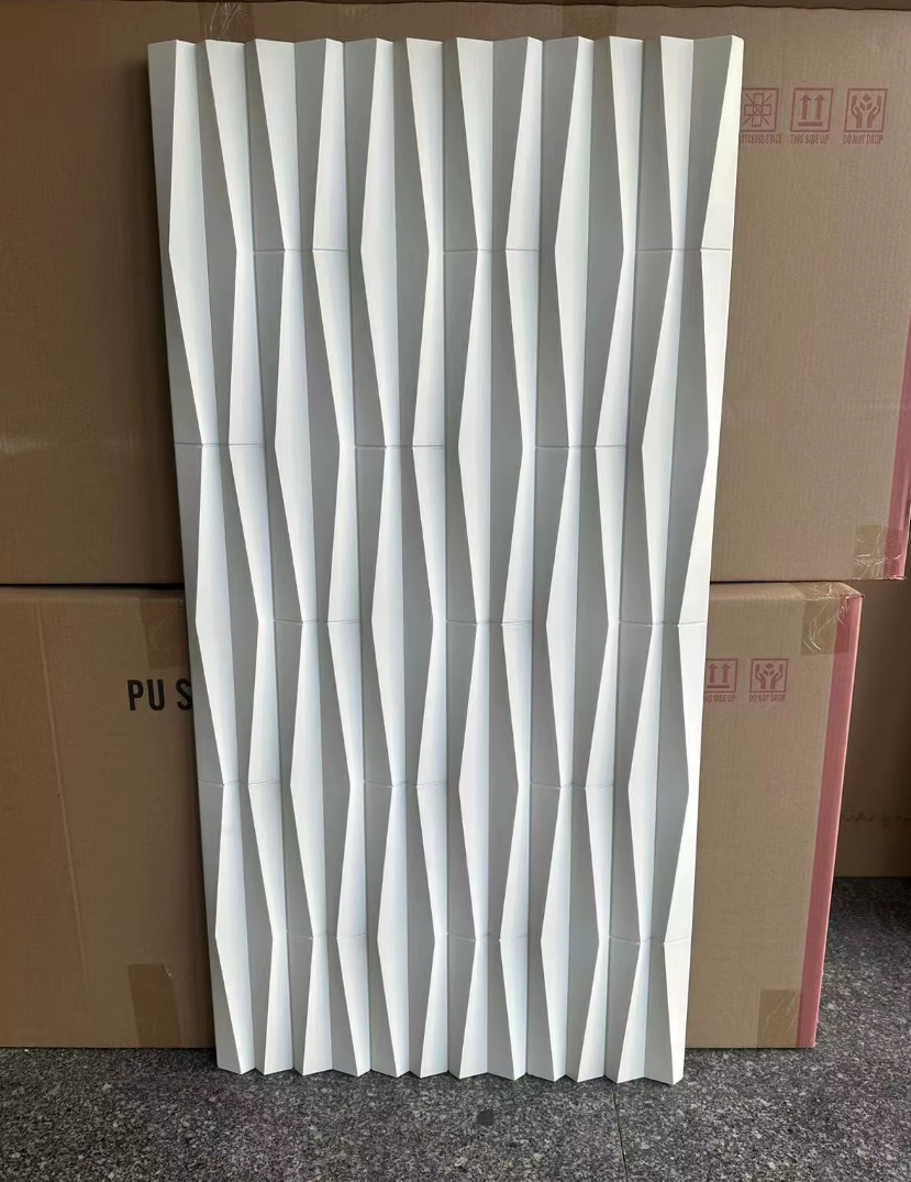 A white decorative panel with a geometric, 3D wave pattern leaning against cardboard boxes.