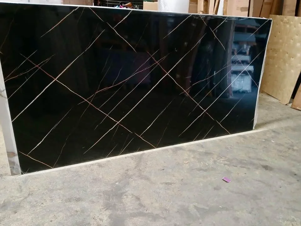 Black marble slab with white and copper veining, leaning against a wall in a workshop.