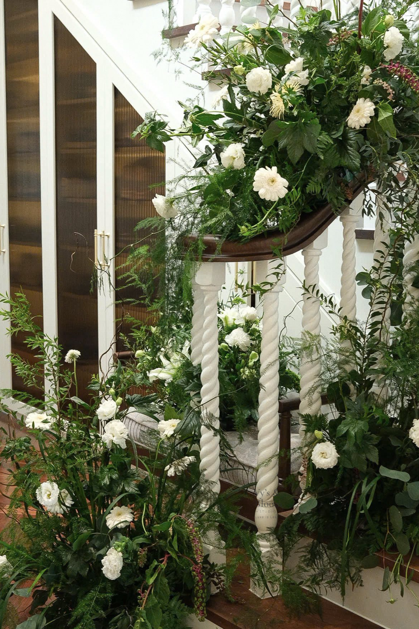 A staircase decorated with white flowers and green foliage, with a white railing featuring twisted spindles.