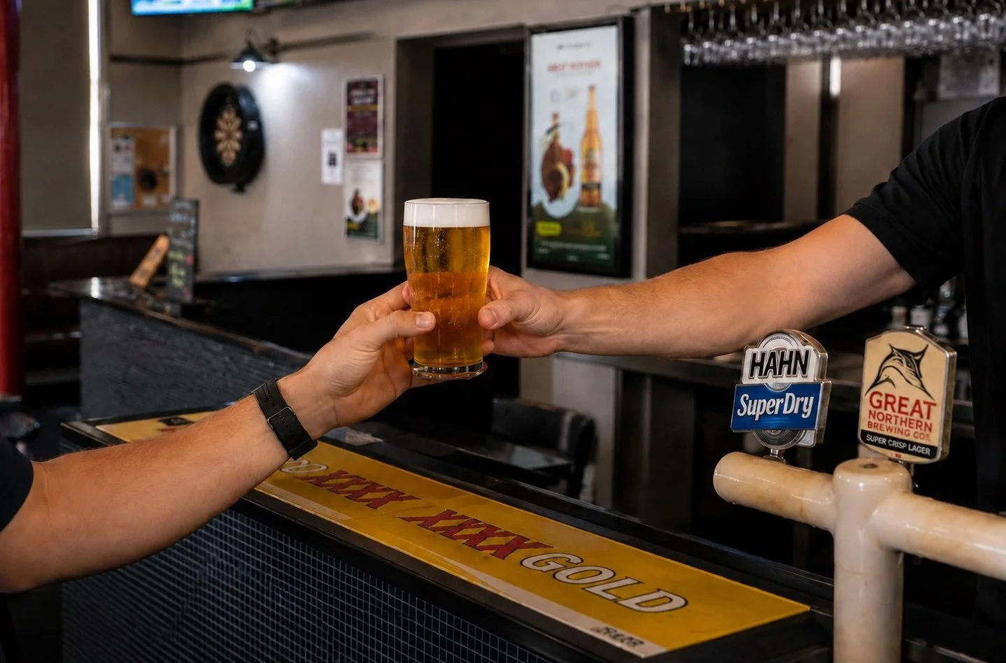 Person at bar handing over a glass of beer to another person.