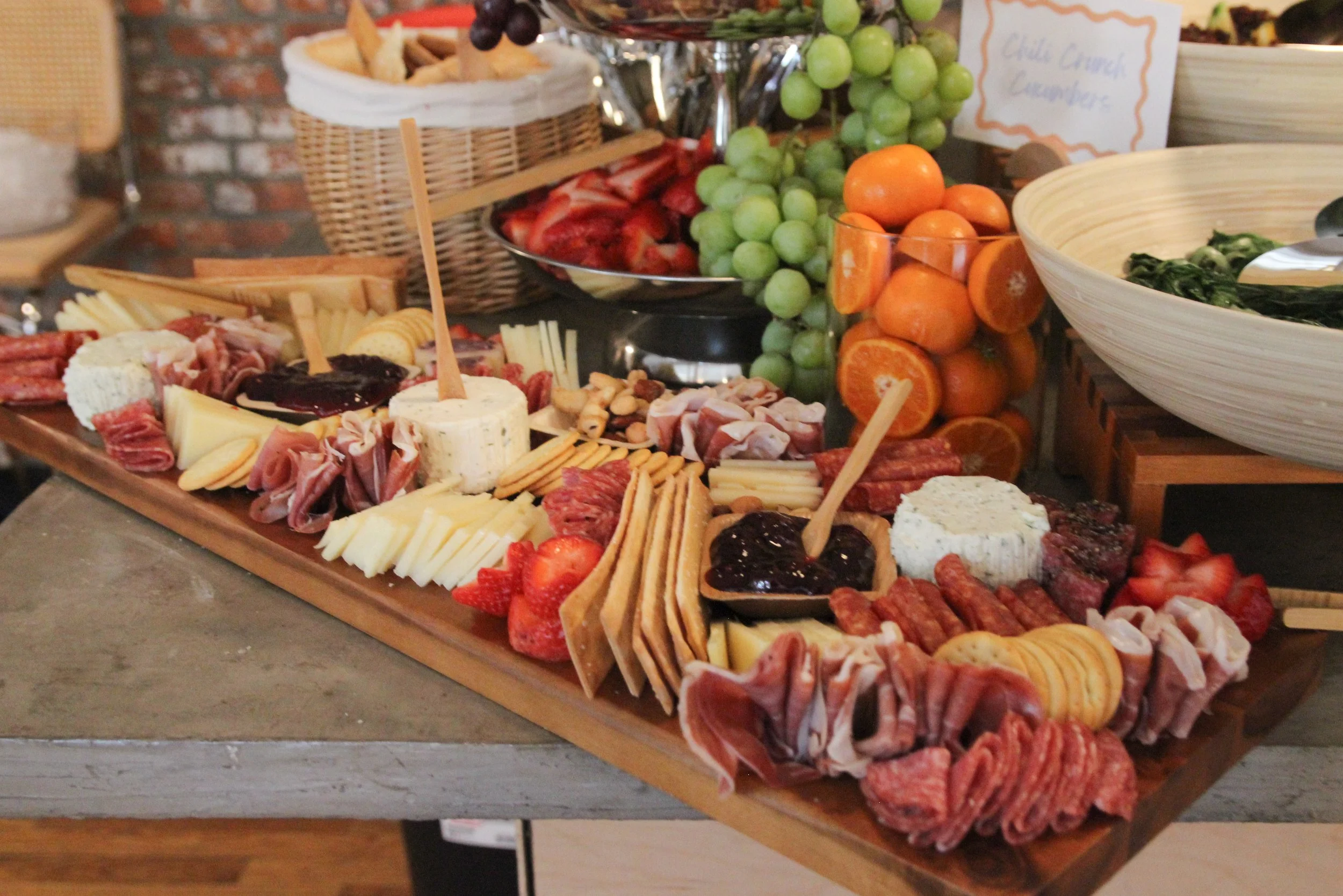 Charcuterie board with cheeses, cured meats, strawberries, and crackers at a buffet.