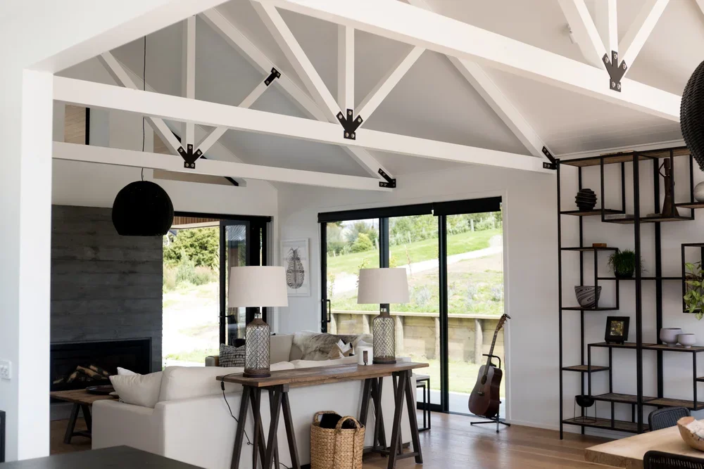 Living room with white ceiling beams, large sliding glass doors, contemporary decor, and a guitar on a stand near the window.