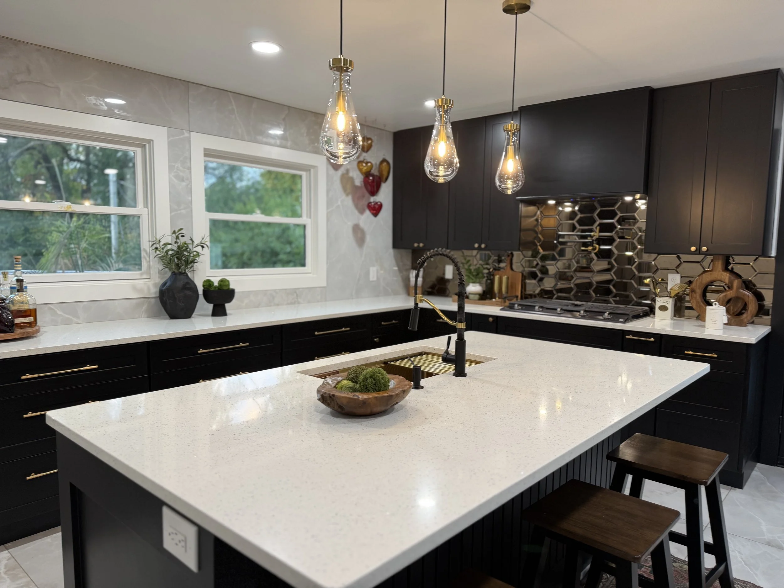 Modern kitchen with white countertops, black cabinetry, pendant lighting, and decorative elements.