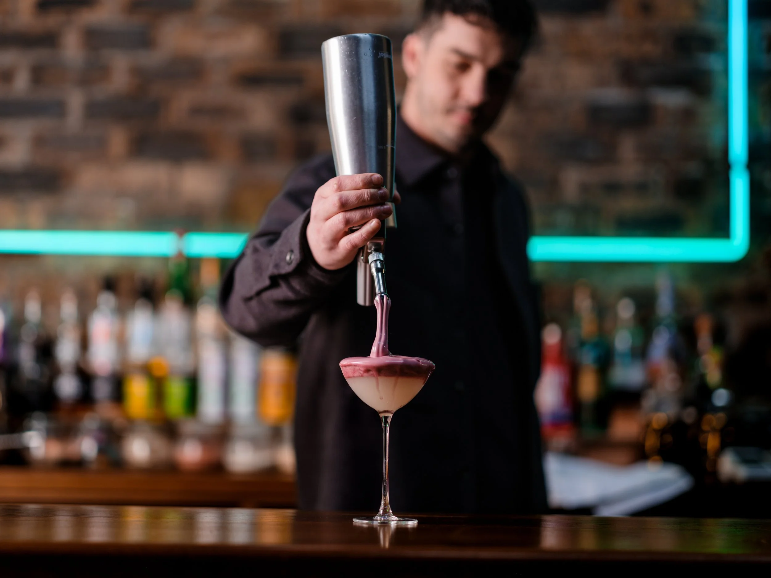 bartender finishing a cocktail with a raspberry espuma