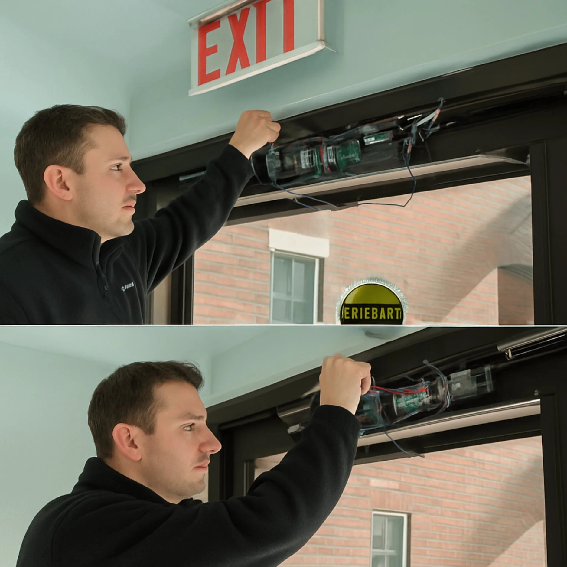 A man working on a hanging door opener device, with wires and electronic components, near an exit sign on the wall.