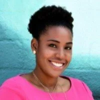 Headshot of smiling female tutor with long braids wearing a lanyard.